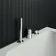 Wannenrandarmatur in Chrom von Ideal Standard, bestehend aus drei Komponenten mit Handbrause und Umsteller, montiert auf einer weißen Badewanne vor schwarzer Kachelwand.